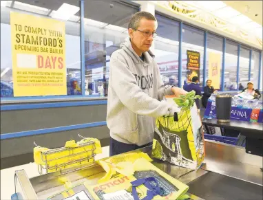  ?? Matthew Brown / Hearst Connecticu­t Media ?? Nick D’Alessan, of Stamford, bags his own groceries using recyclable bags after shopping at Shop Rite in Stamford.