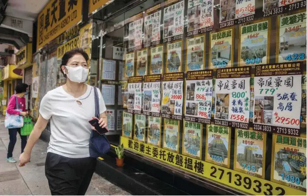  ?? Agence France-presse ?? ↑
A woman walks past a real estate agent in Hong Kong.