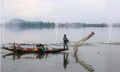  ?? ?? A fisher casts a net into Dal Lake on a cloudy day in Srinagar, India. Photograph: Farooq Khan/EPA