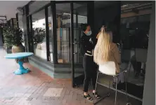  ?? Scott Strazzante / The Chronicle ?? Sue Kim of Tiara's Hair Extensions works on a client outside the darkened salon during a power shutoff in Orinda.