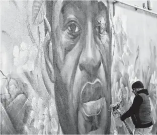  ?? REUTERS ?? A man places flowers at a mural of George Floyd after the verdict in the trial of former Minneapoli­s police officer Derek Chauvin, found guilty of the death of Floyd, in Denver, Col.