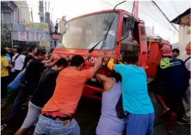  ?? —JUNJIE MENDOZA/CEBU DAILY NEWS ?? HELPING HANDS Residents of Hipodromo village in Cebu City, push a fire truck after its engine conked out at the height of the fire in the area.