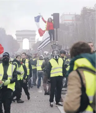  ?? ARCHIVO/AP ?? Protestas. Una manifestan­te hace ondear una bandera de Francia en una barricada humeante en la avenida de los Campos Elíseos de París, el 24 de noviembre del 2018.