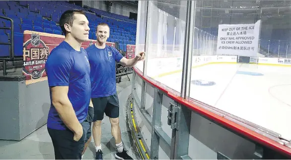  ?? PHOTOS: JEFF VINNICK/NHLI VIA GETTY IMAGES ?? Vancouver Canucks Bo Horvat, left, and Daniel Sedin check out the foggy ice surface — and the bilingual sign on the glass — before the team’s practice at Mercedes-Benz Arena in Shanghai on Tuesday. The Canucks and Los Angeles Kings are in China to play...