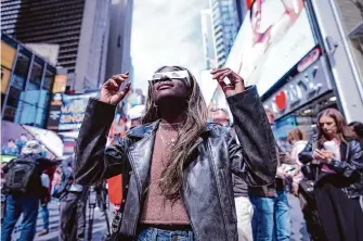  ?? Peter K. Afriyie/Associated Press ?? A woman watches the phenomenon from New York’s Times Square. It will be 21 years before the United States sees another total solar eclipse on this scale.
