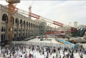  ?? Ahmed Farwan / AFP / Getty Images ?? Muslim pilgrims walk past the crane that collapsed at the Grand Mosque in the holy city of Mecca. More than 100 people were killed when the crane fell during a violent storm.