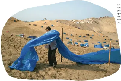  ??  ?? Un hombre marca con una banda de plástico el terreno que acaba de invadir en Lima (Perú) en abril de 2021.