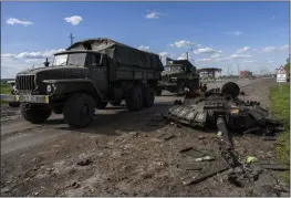  ?? BERNAT ARMANGUE — THE ASSOCIATED PRESS ?? Ukrainian army vehicles drive past the remains of a Russian tank in north Kharkiv, east Ukraine, on Friday.