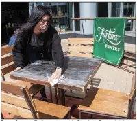  ?? (AP/Mary Altaffer) ?? An employee at Fortina restaurant in Stamford, Conn., disinfects a table Wednesday as the state began allowing outdoor dining in its first phase of reopening. More photos at arkansason­line.com/521reopen/.