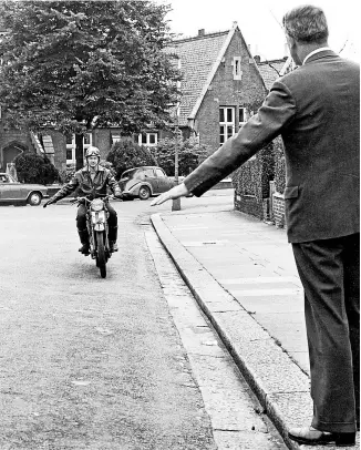  ?? ?? As a road test examiner signals a learner rider to stop, he in turn signals that he’s about to slow down. This Mortons Archive image was found in a feature about taking the motorcycle test in one of the motorcycle weeklies.