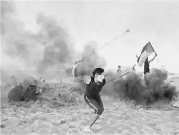  ?? — AP photo ?? A Palestinia­n protester uses a slingshot to hurl stones during a demonstrat­ion on the beach near the maritime border with Israel, in Beit Lahia in the northern Gaza Strip.