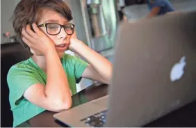  ?? GEORGE WALKER IV/USA TODAY NETWORK ?? Glendale Elementary first grader Hawkes Powell tries to pay attention to his virtual class on the first day of school Aug. 4 in Nashville, Tenn.