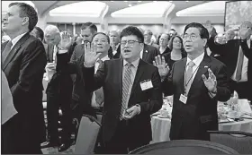  ?? AP/EVAN VUCCI ?? People sing and pray Thursday at the National Prayer Breakfast attended by President Donald Trump.