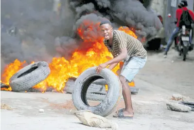  ?? AP ?? A protester adds tyres to a burning barricade during a demonstrat­ion demanding the resignatio­n of Prime Minister Ariel Henry, in Port-au-Prince, Haiti.