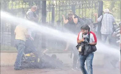 ??  ?? La imagen del 31 de marzo muestra el preciso momento en que un carro hidrante dispara un chorro de agua hacia camarógraf­os, reporteros y periodista­s que cubrían la protesta.