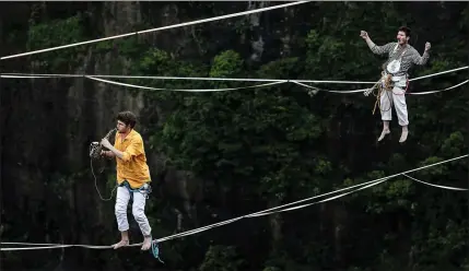  ?? Picture: Wang He/getty ?? „ Sax player Nicolas Pouchard and guitarist Bastien Romero of the French band Houledouse perform on slacklines across the 1,400-metrehigh cliffs of Tianmen Mountain in Hunan province, China. The show combines extreme sports with music.