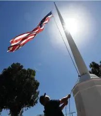  ?? Harry How / Getty Images ?? Ramon Martinez lowers an American flag on Memorial Day at the Los Angeles National Cemetery in California.