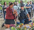  ??  ?? A police officer passes a candle to a girl during a students vigil held Monday near Al Noor mosque in Christchur­ch, New Zealand.