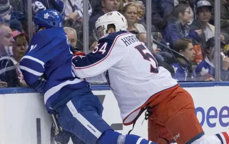  ?? CARLOS OSORIO/TORONTO STAR ?? Leafs rookie Zach Hyman, left, is checked into the boards by Blue Jackets defenceman Scott Harrington during the first period at the ACC on Sunday.