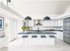  ??  ?? The family says the kitchen is the epicenter of the 1,100-square-foot home. The bar stool cushions are covered in wetsuit material, designed to hold up during a post-swim meal. At $2,500 apiece, the Flos pendant lights above the island were one of the...