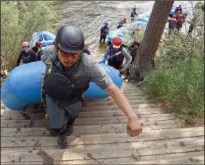  ??  ?? Kevin Perez, a rafting guide for Rocky Mountain Adventures, pulls an inflatable boat out of the water June 23 after taking a group down the river.