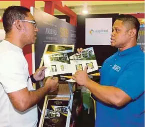  ?? PIX BY RASUL AZLI SAMAD ?? SPNB Aspirasi project manager Mohamad Ismail Basiron (right) showing a special package offered by his company to MyRumah project manager Mohd Haslan Abdul Abbas at the New Straits Times Press MyRumah Property Showcase 2018 in Melaka yesterday.