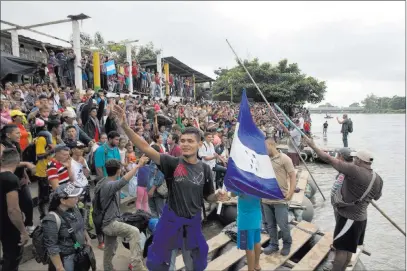  ??  ?? The Associated Press Hundreds of Honduran migrants stand Thursday at the shore of the Suchiate River on the border between Guatemala and Mexico. Some in the caravan broke through a border fence Friday.