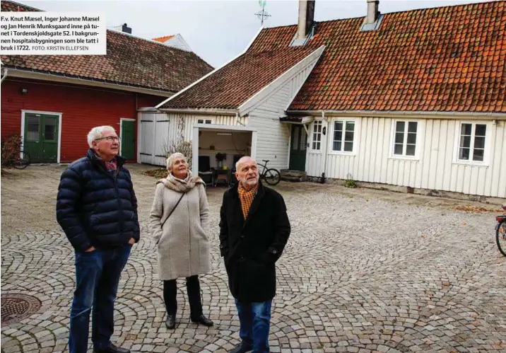  ?? FOTO: KRISTIN ELLEFSEN ?? F.v. Knut Maesel, Inger Johanne Maesel og Jan Henrik Munksgaard inne på tunet i Tordenskjo­ldsgate 52. I bakgrunnen hospitalsb­ygningen som ble tatt i bruk i 1722.