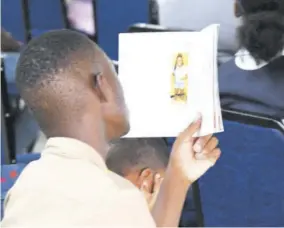  ?? (Photo: Joseph Wellington) ?? A student of Kingston Technical High looks at a photo of his school mate Michion Campbell during her funeral service in November 2022. Campbell was fatally stabbed during a dispute with one of her peers last September.