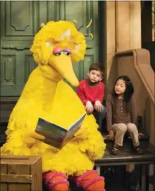  ?? THE ASSOCIATED PRESS — MARK LENNIHAN ?? In this April 10, 2008file photo, muppet character Big Bird reads to Connor Scott and Tiffany Jiao during a taping of the children’s program “Sesame Street” in New York.