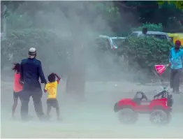  ?? — PTI ?? People walk through a sudden dust storm in New Delhi on Saturday.