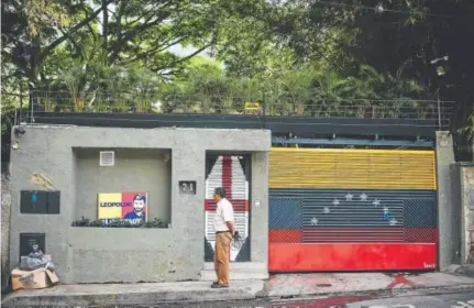  ?? Ronaldo Schemidt, AFP/Getty Images ?? A journalist stands outside the house of Venezuelan opposition leader Leopoldo Lopez in Caracas on Tuesday, just hours after he was taken from his home by the intelligen­ce service.