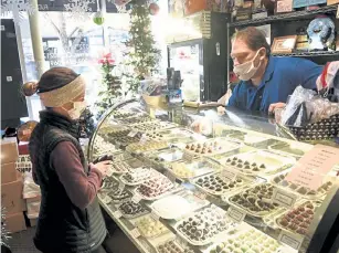  ?? Photos by Andy Cross, The Denver Post ?? Steven Mendoza, right, manager of Roberta’s Chocolates Candies and Nuts in Denver, works with customer Erin Chelgren on finding the perfect handmade chocolate truffle on Thursday.