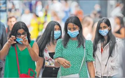  ?? Frank Augstein The Associated Press ?? Shoppers wear face coverings Friday along Oxford Street in London. New rules on wearing masks in England are in force.