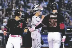  ?? ROSS D. FRANKLIN/AP ?? ARIZONA DIAMONDBAC­KS’ ALEK THOMAS (LEFT) celebrates with teammate Pavin Smith (26) after scoring as Colorado Rockies catcher Dom Nunez (center) pauses at home plate in the fifth inning of a game on Sunday in Phoenix.