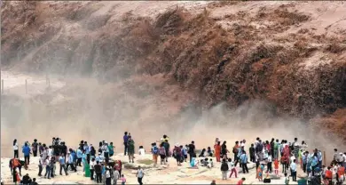  ?? LYU GUIMING/ FOR CHINA DAILY ?? The Yellow River, tremendous­ly swollen from heavy rain upstream, gushes furiously over Hukou Waterfall in Shanxi province on Thursday, attracting scores of tourists to the site.