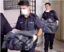  ??  ?? Police removing the remains of the baby and toddler from the apartment unit yesterday.