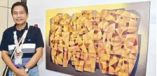  ??  ?? Ric Ico beside his painting “Community.” The artist from La Union’s forte is neocubism with a touch of realism.