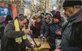  ?? IVOR PRICKETT/THE NEW YORK TIMES ?? Nearly a year after Russia invaded Ukraine, people line up for jars of soup Wednesday during a humanitari­an aid distributi­on event in Kherson, Ukraine.
