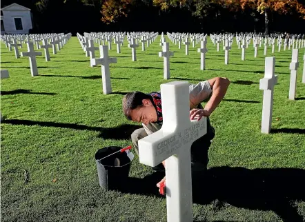  ?? AP ?? A cemetery employee cleans the grave marker of an American serviceman killed in World War I ahead of the armistice commemorat­ions at the American Cemetery in Suresnes, on the outskirts of Paris.