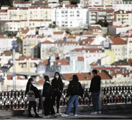 ?? ARMANDO FRANCA AP ?? A group of young people wearing face masks chat at a viewpoint overlookin­g Lisbon's old center, a spot popular with tourists and now nearly deserted.