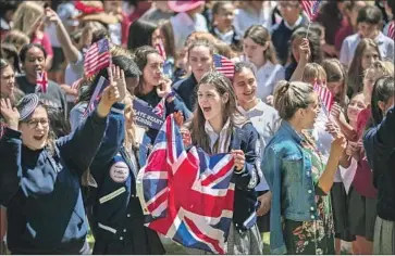  ?? David McNew AFP/Getty Images ?? STUDENTS AT Immaculate Heart Catholic School wave British and U.S. f lags Tuesday as they celebrate this weekend’s wedding of Prince Harry and actress Meghan Markle, who graduated from the L.A. school in 1999.
