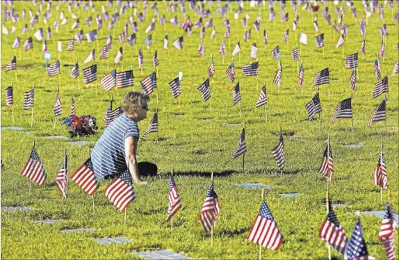  ?? Richard Brian Las Vegas Review-Journal @vegasphoto­graph ?? Las Vegas resident Mary Beth Platzkow on Saturday visits the grave of her late husband, Vietnam veteran Kenneth Platzkow, at the Southern Nevada Veterans Memorial Cemetery in Boulder City.