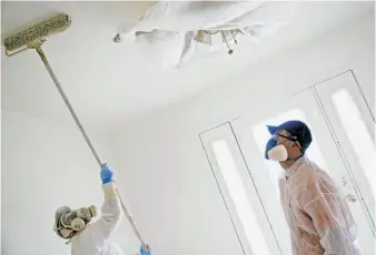  ??  ?? Brothers Jose (left) and Osvaldo Salgado paint the interior of the Santa Rosa home Praxis Capital bought and plans to rent until it appreciate­s enough to sell.