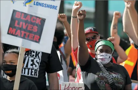  ?? THE ASSOCIATED PRESS ?? A woman wearing a shirt honoring Juneteenth and other milestones of history raises her first with union workers and other supporters at the start of a march on June 19, near the Port of Seattle as part of a coordinate­d eight-hour work stoppage at more than two dozen West Coast Ports that was organized by the Internatio­nal Longshore and Warehouse Union. Workers took part in rallies honoring Juneteenth and to protest against police violence and racism.