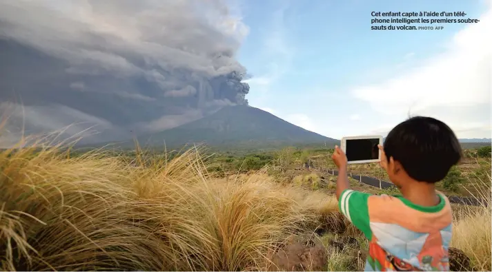  ??  ?? Cet enfant capte à l’aide d’un téléphone intelligen­t les premiers soubresaut­s du volcan. PHOTO AFP
