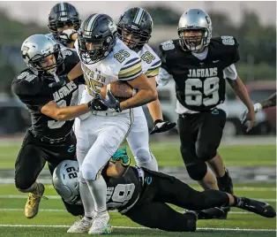  ?? JIM WEBER/THE NEW MEXICAN ?? Demons running back Daniel Wright plows through the Jaguars’ Angelo Baker, left, and Fabian Ryan on Friday at Jaguar Field. Santa Fe High won 48-28.