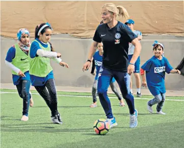  ??  ?? Child’s play: Katie Chapman thrills some young girls by playing football on her visit to a camp near the Jordan-Syria border