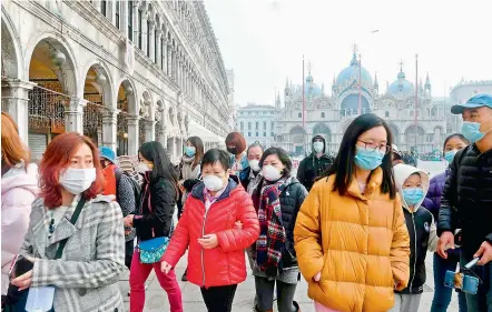  ?? — AFP ?? Tourists wearing protective facemasks visit the Piazza San Marco, in Venice, on Monday during the usual period of the Carnival festivitie­s, with the last two days having been cancelled due to outbreak of novel coronaviru­s.