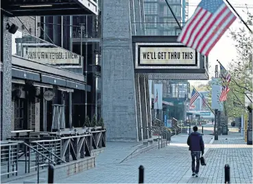  ?? /Bloomberg ?? Abandoned: A pedestrian walks near a ‘We’ll Get Through This’ sign displayed on the marquee outside The Anthem music venue in The Wharf neighbourh­ood of Washington, DC on Tuesday.